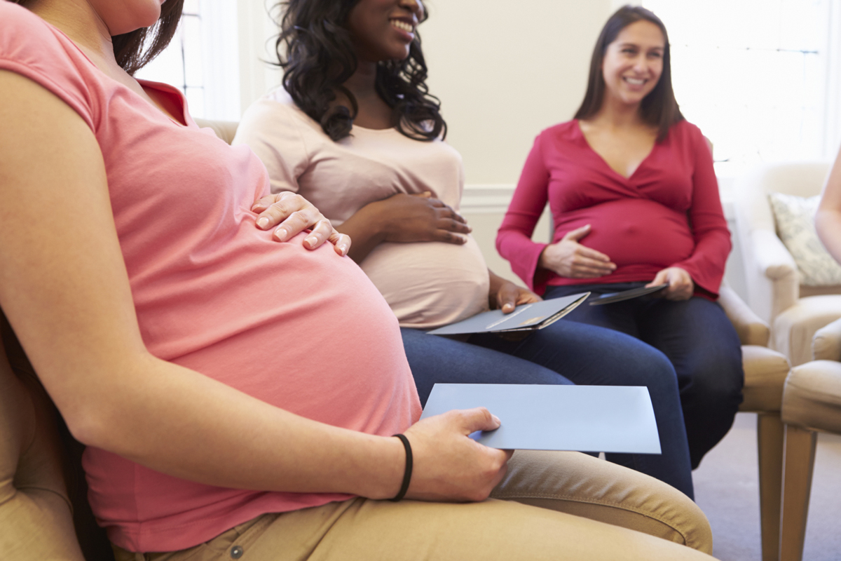 closeup of torsos of 3 pregnant women sitting