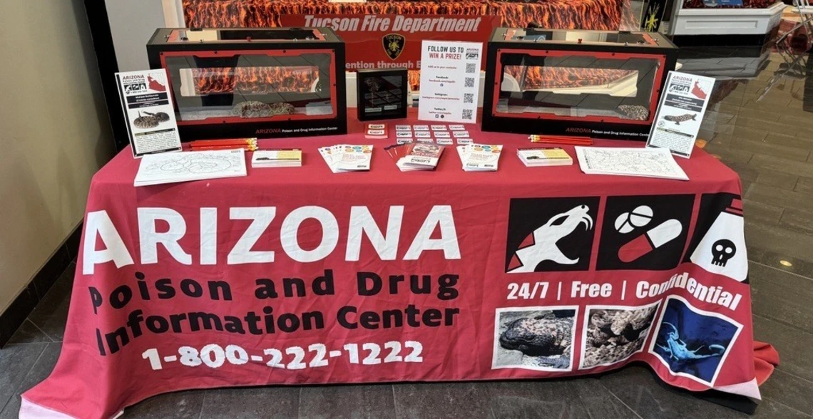 Arizona Poison and Drug Information Center outreach table with educational materials, display enclosures, and promotional items set up in a public space.