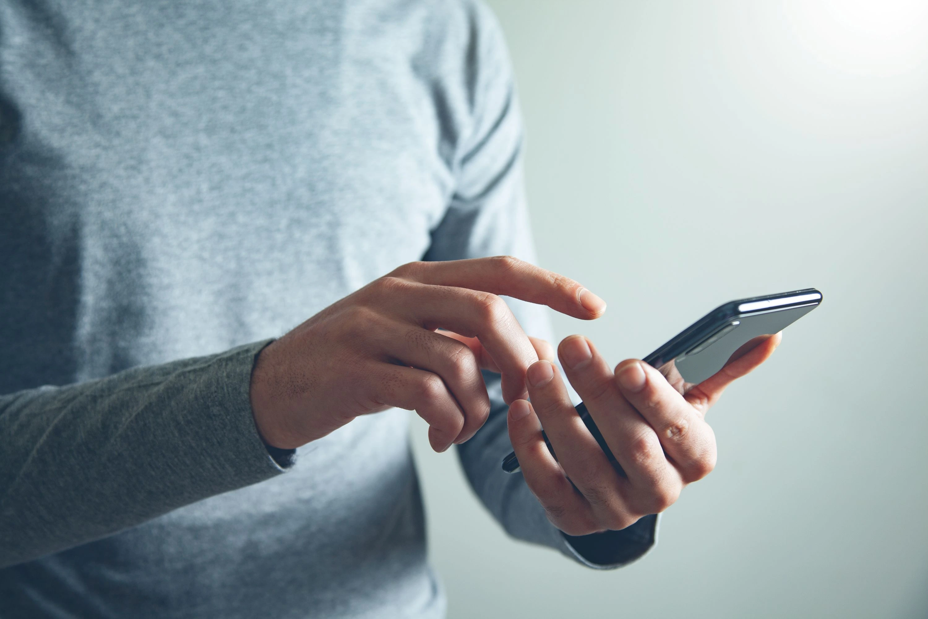Person using a smartphone, touching the screen with one hand.