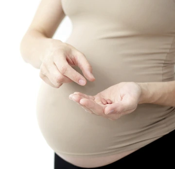 Pregnant woman holding pills in her hand.